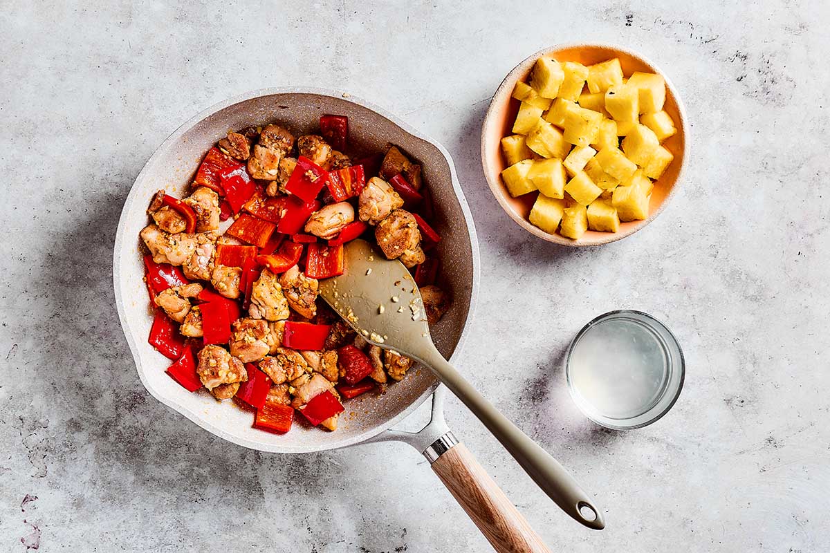 chicken and bell peppers sauteing in skillet.