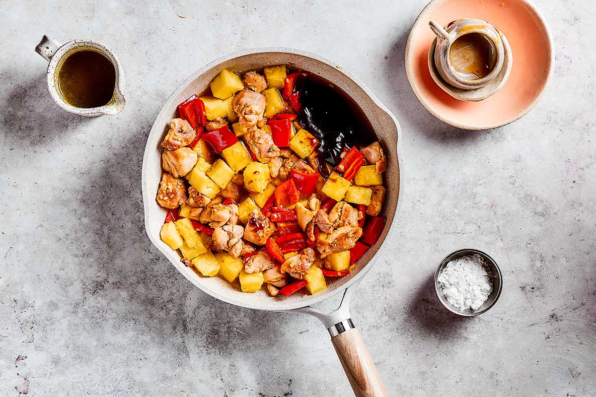 adding sauce to pineapple and bell peppers in skillet.