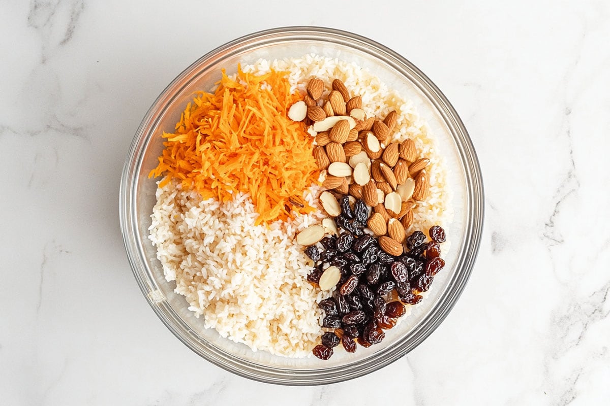 grated carrots, rice, raisins, and almonds in a bowl.