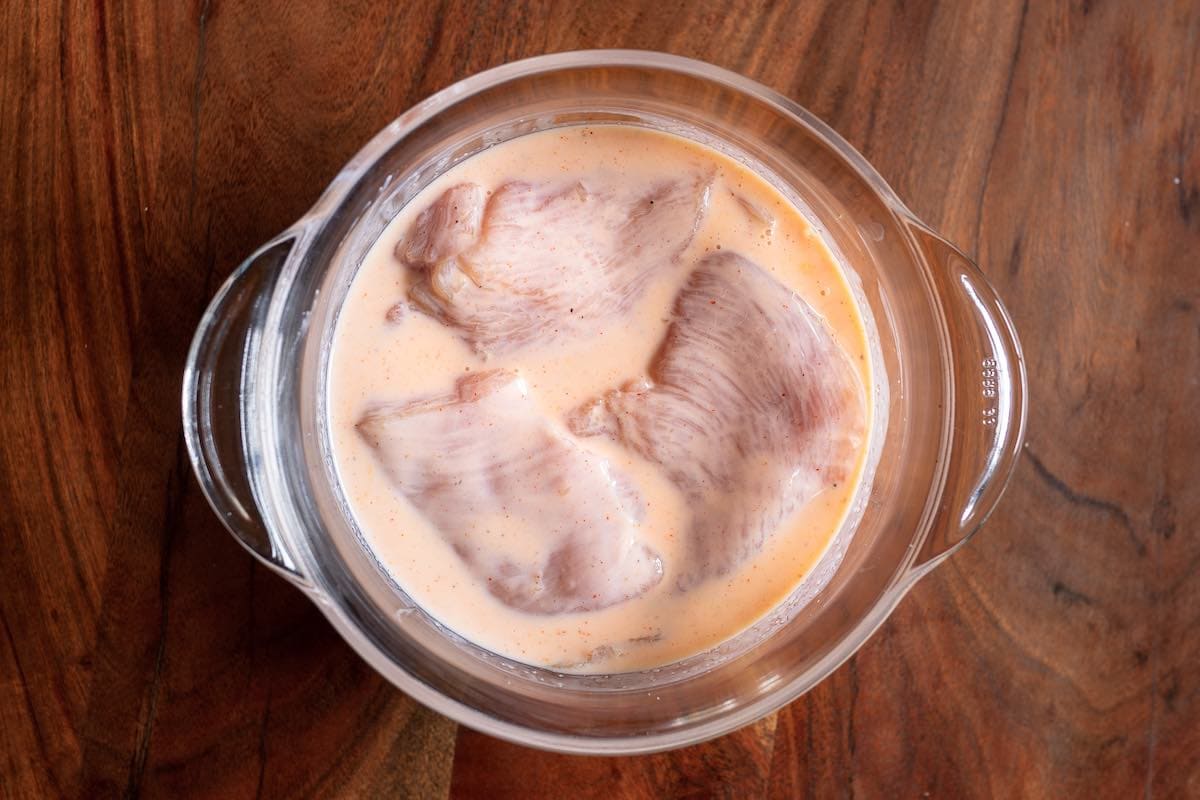 raw chicken marinating in a bowl.