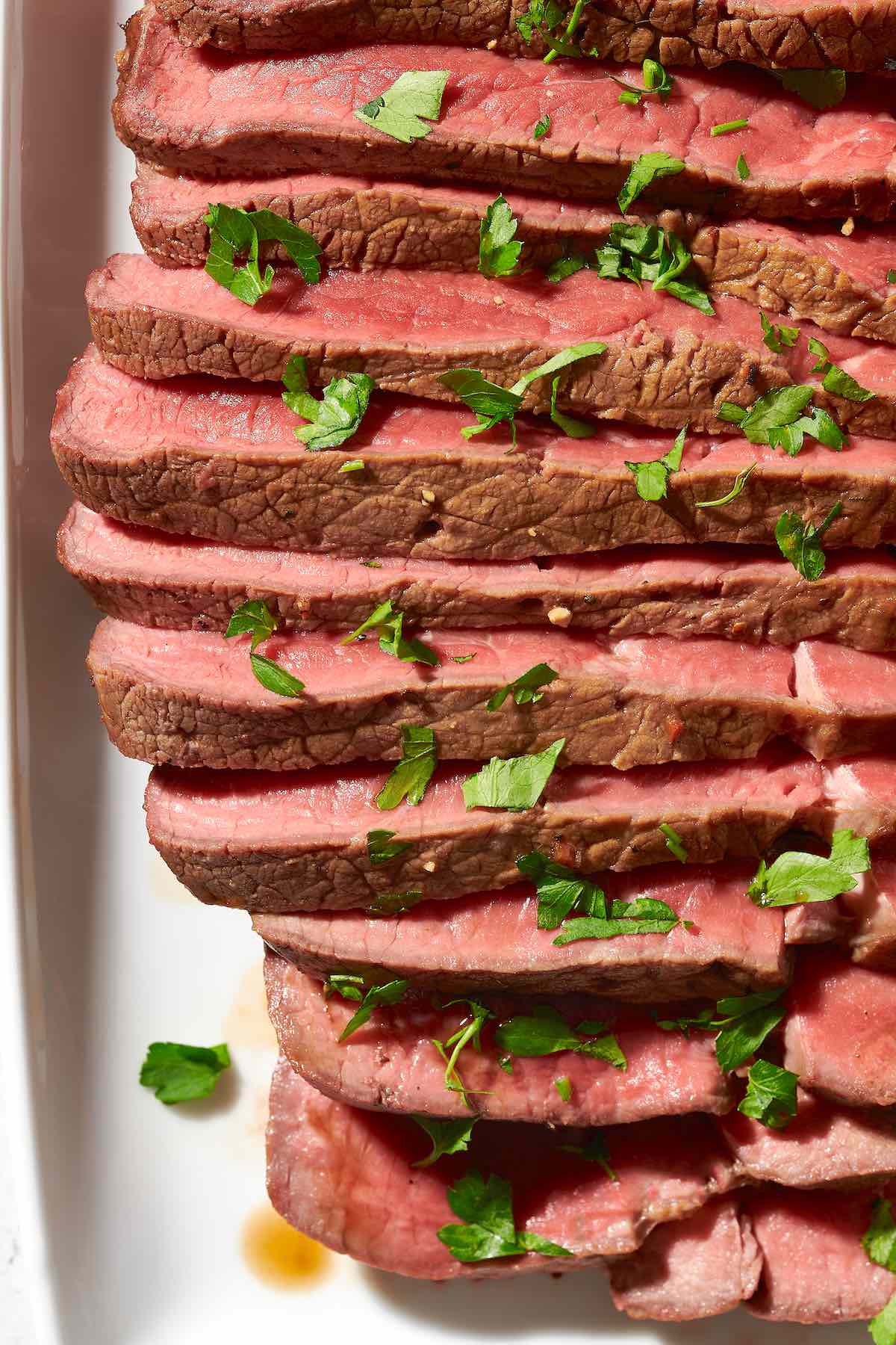 sliced london broil with herbs on top.