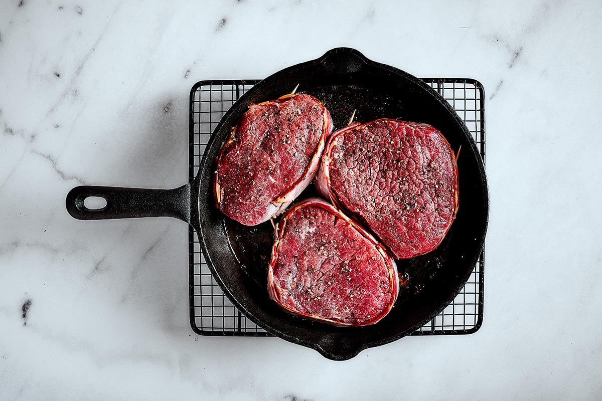 raw filet mignon steaks searing in a skillet.