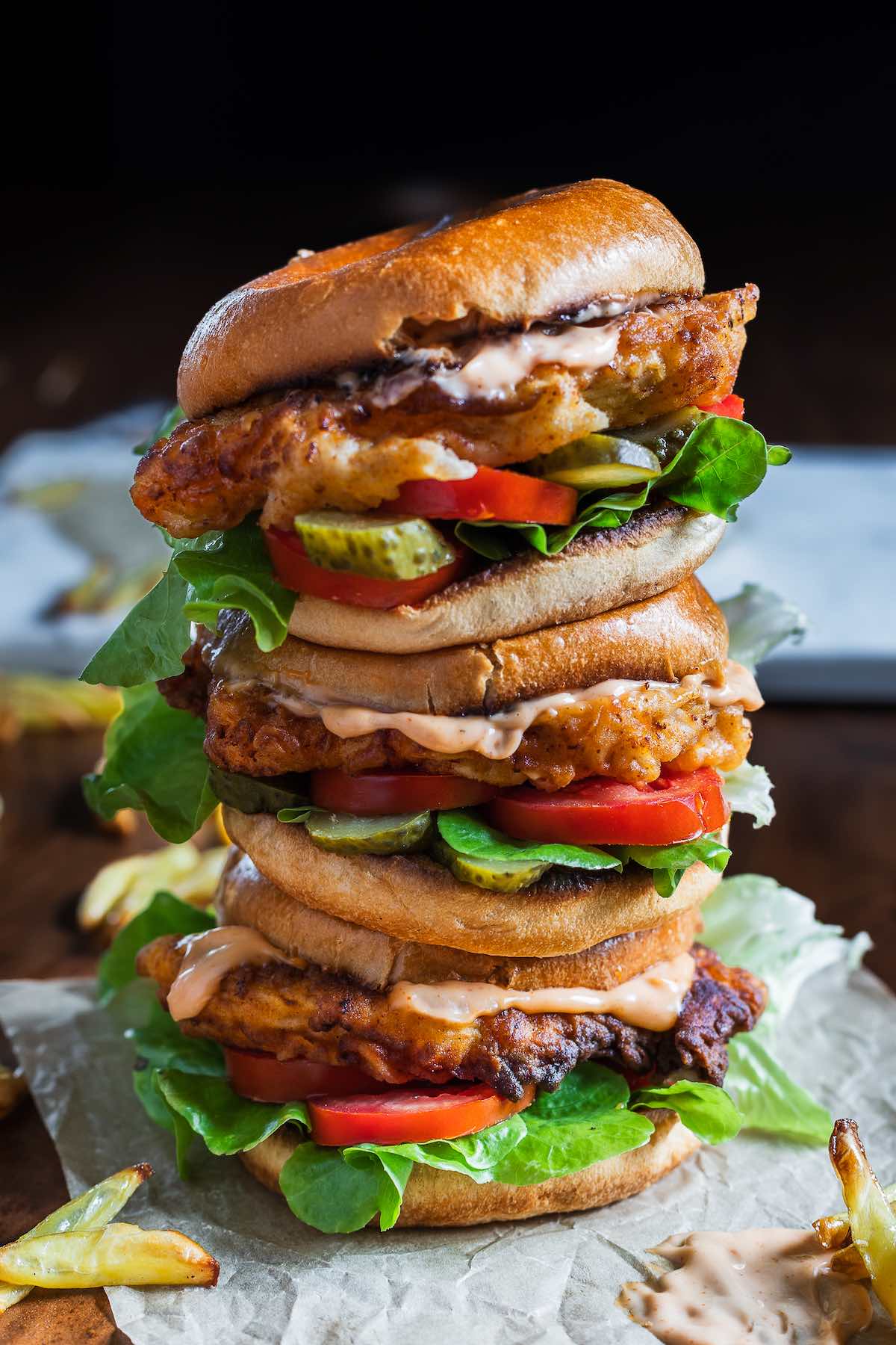 homemade spicy chicken sandwiches with pickles and sauce.