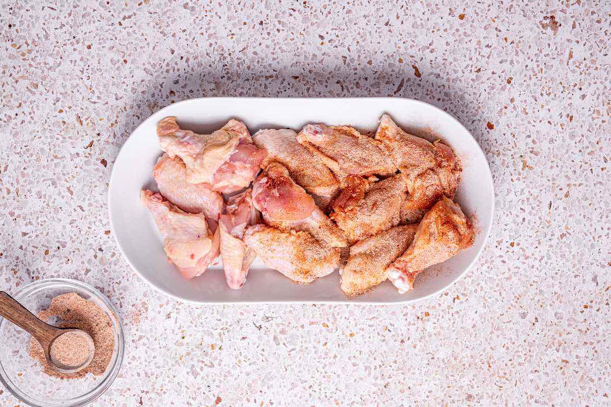 seasoned raw chicken wings on a plate.