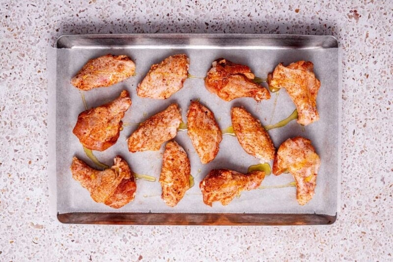 seasoned raw chicken wings on a baking sheet.