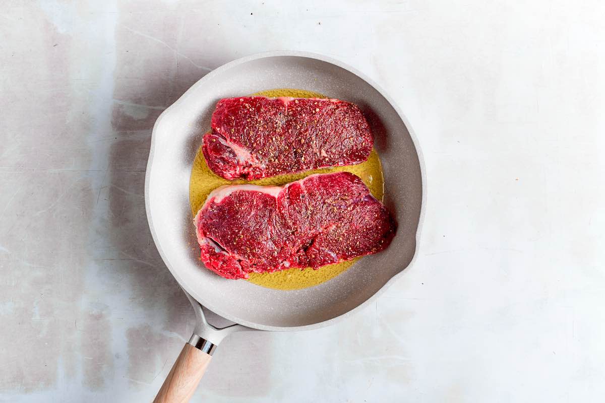 chuck eye steaks cooking in a skillet.