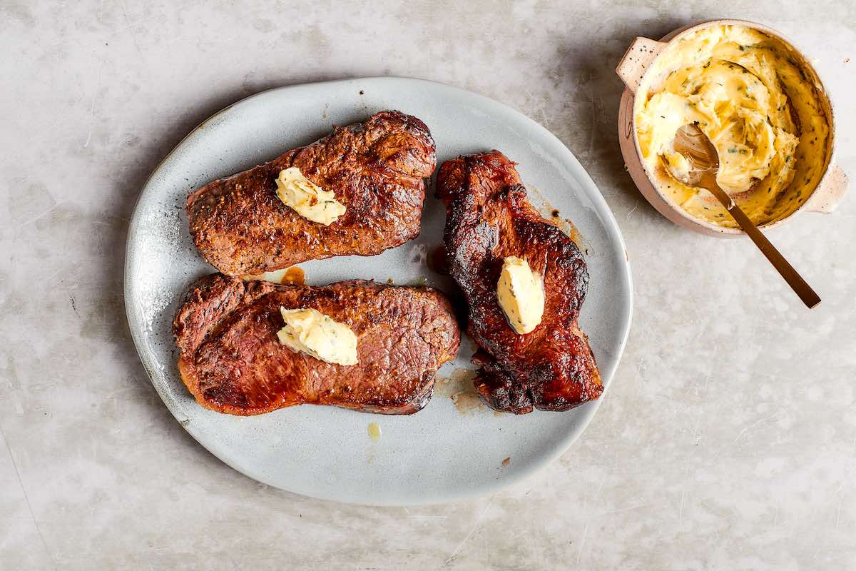 cooked steaks with garlic butter on top.