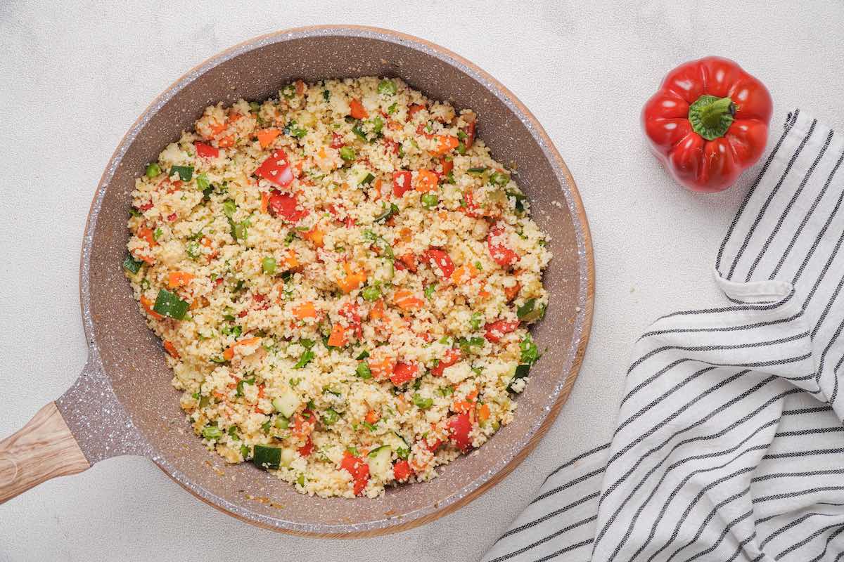 skillet with freshly fluffed couscous and diced vegetables.