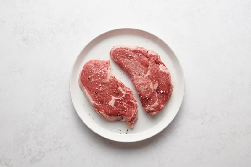 seasoned raw ribeye steaks.