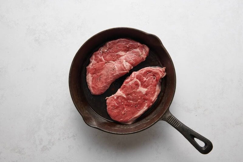 searing ribeye steaks in a skillet.