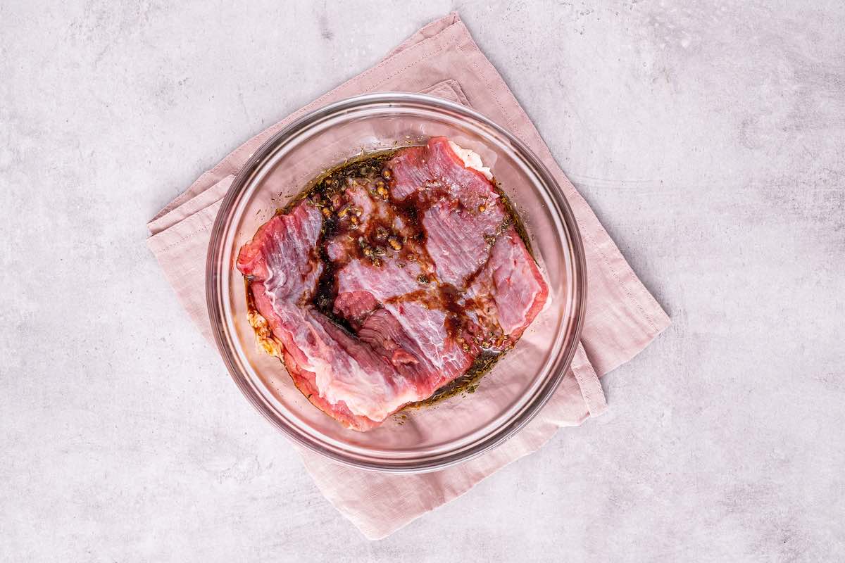 marinated raw skirt steaks in a bowl.