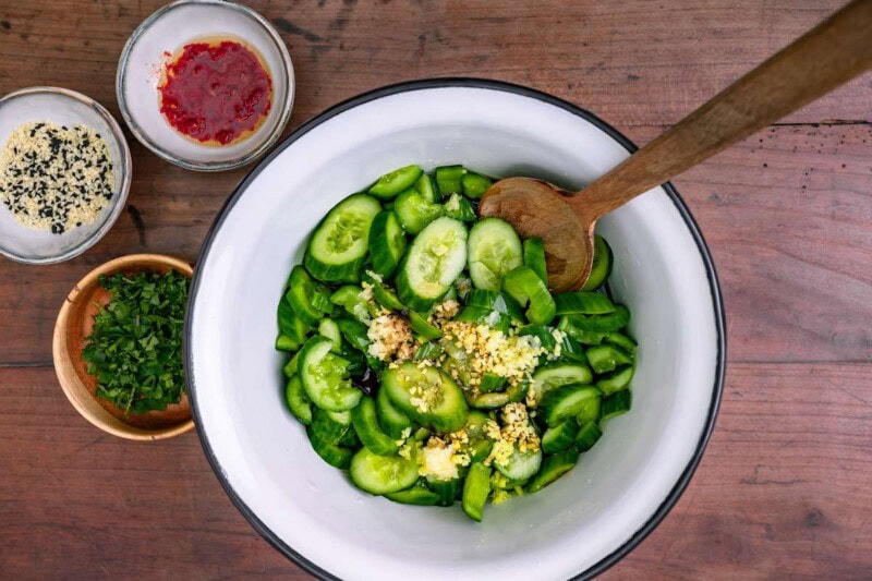 adding dressing to smashed cucumbers.