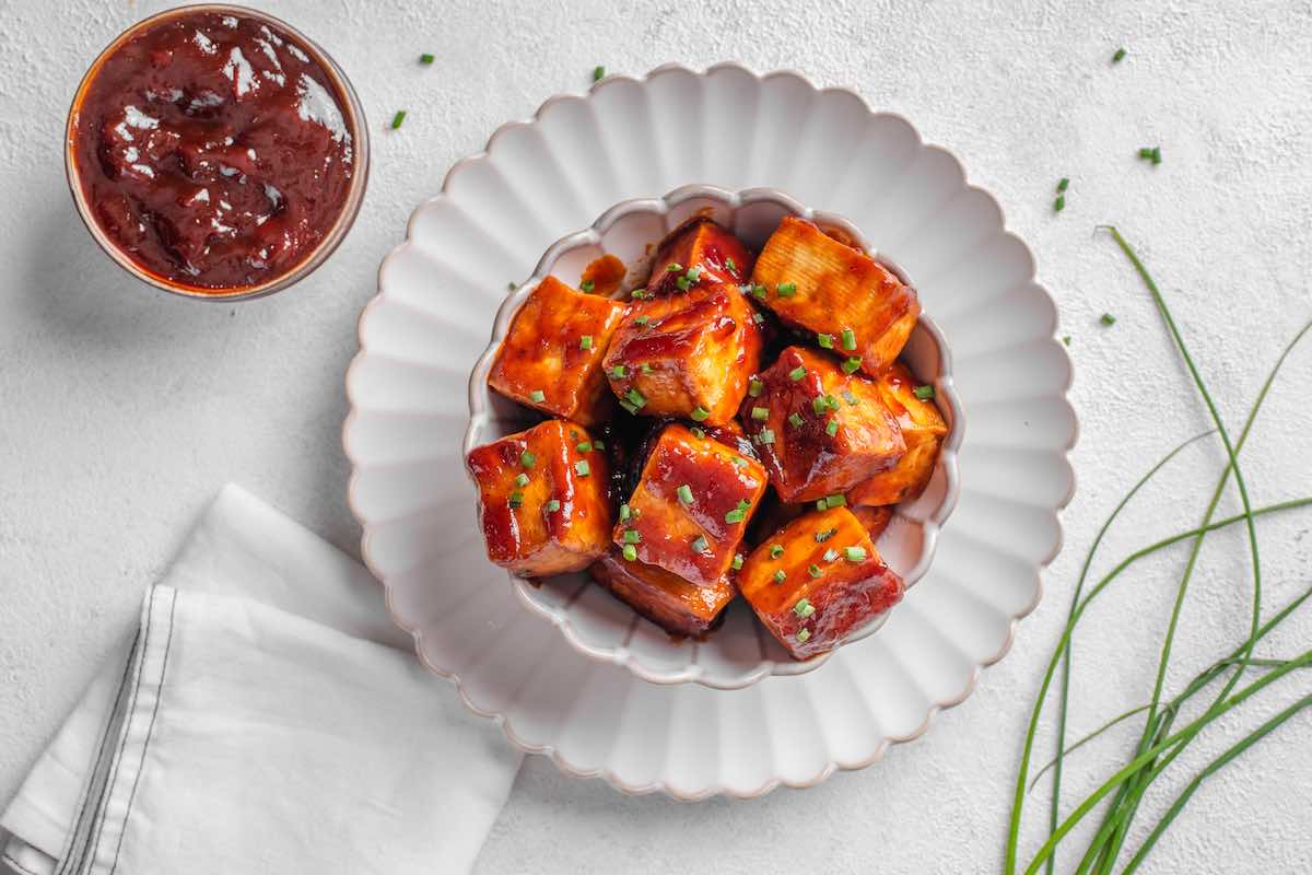 tofu covered in BBQ sauce with fresh herbs on top.