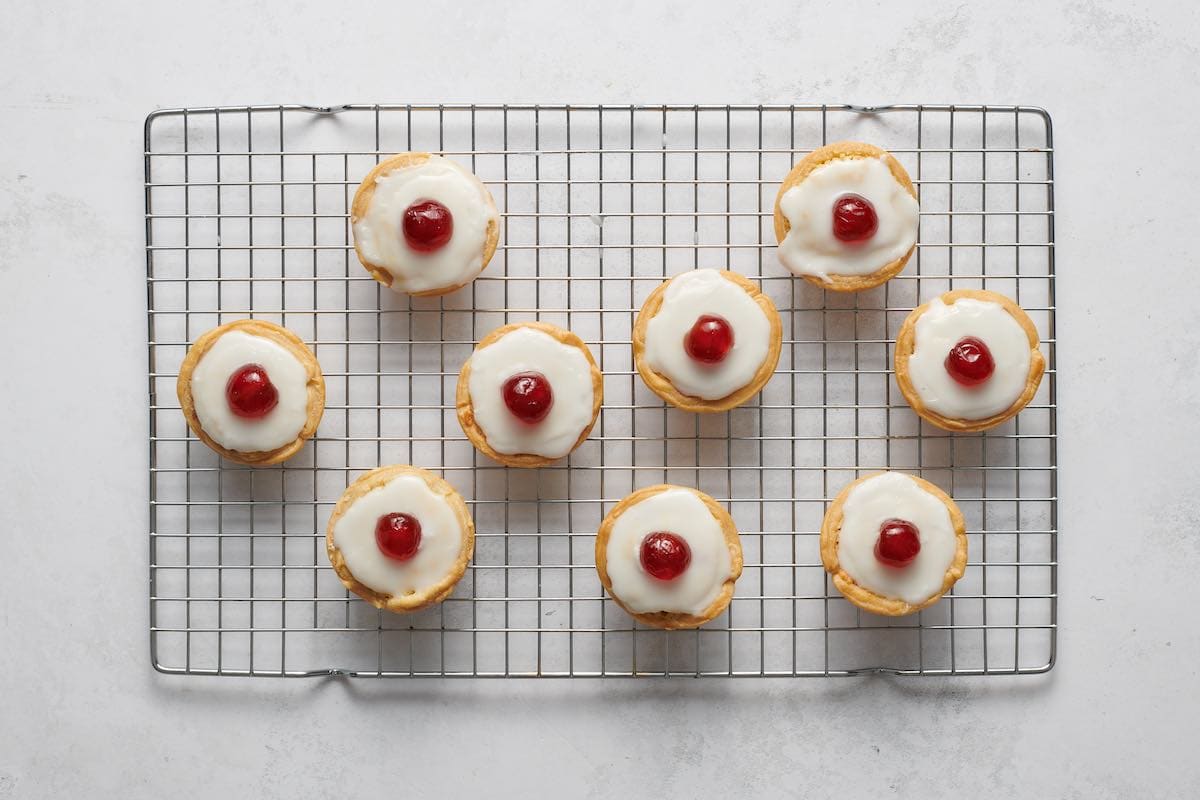 assembled cherry bakewells on wire rack.