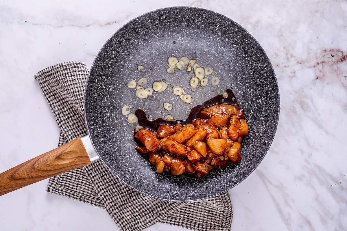 marinated raw chicken and garlic in skillet.