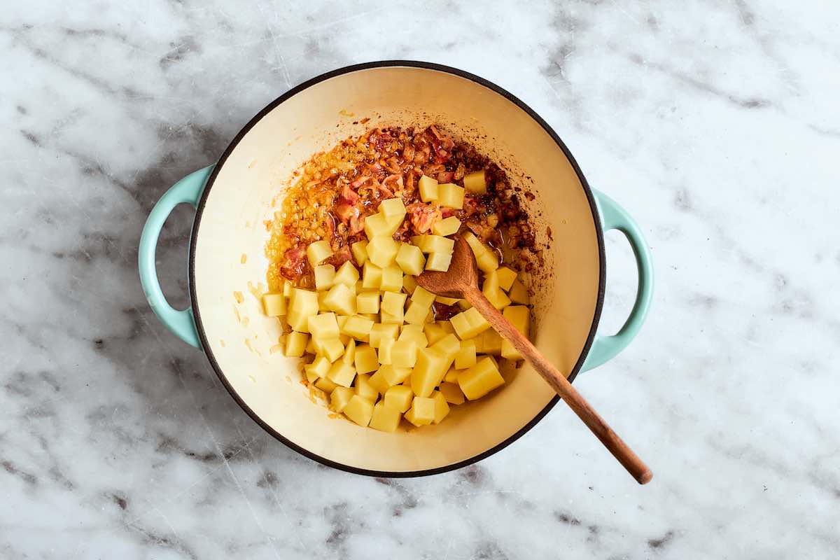 chopped potatoes in Dutch oven with crispy bacon and onion.