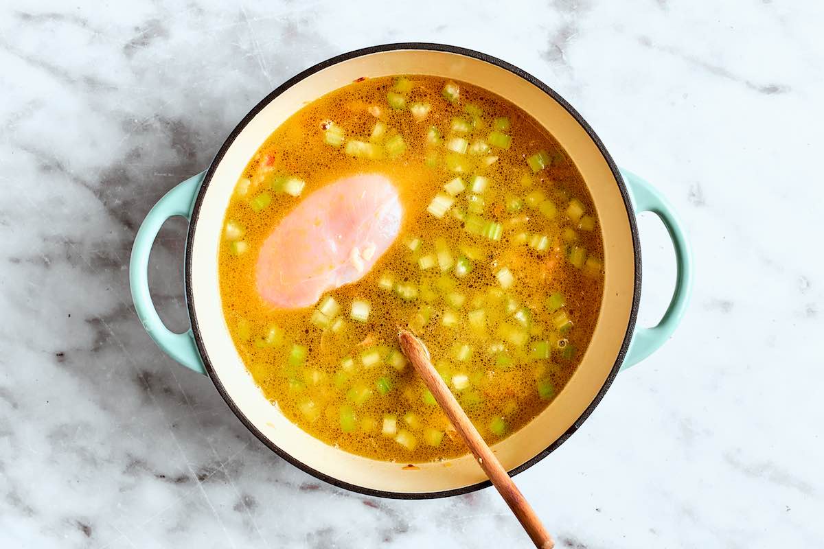 broth, chicken, vegetables, and potato in soup pot.