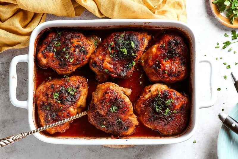 baked honey garlic chicken thighs with fresh herbs on top.