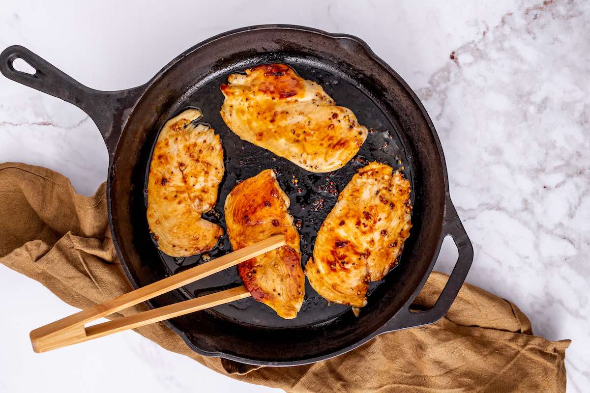 pan frying marinated chicken in a skillet.