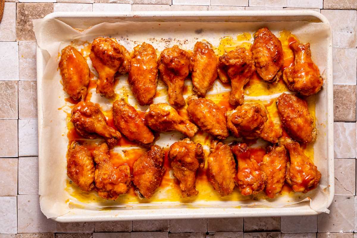 buffalo sauce covered chicken wings on a baking dish.