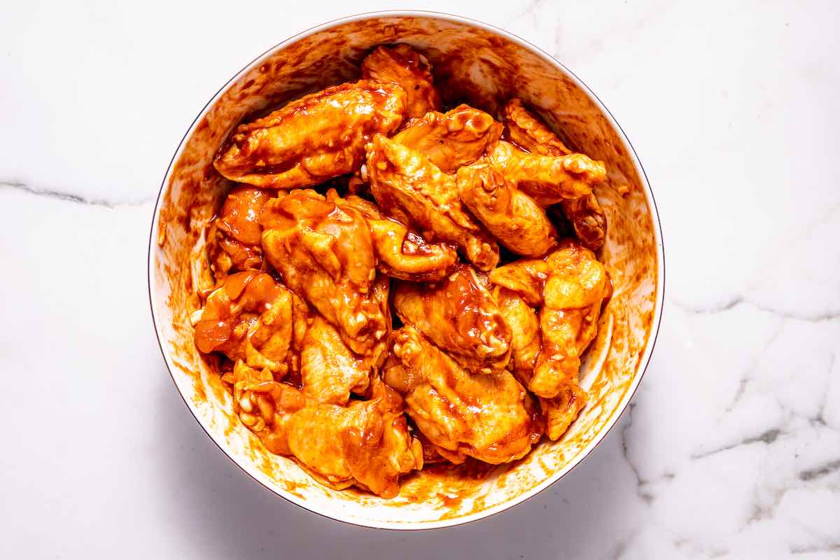 raw chicken wings with marinade in a bowl.