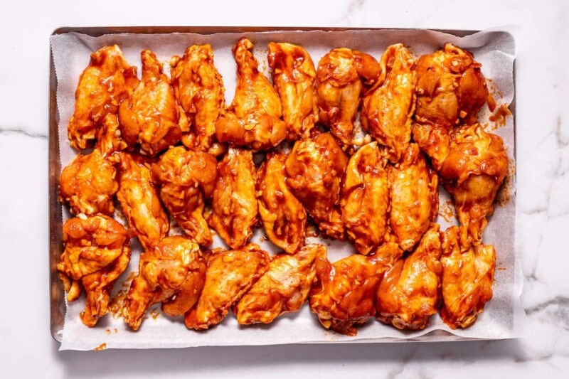 raw marinated wings on a baking sheet.