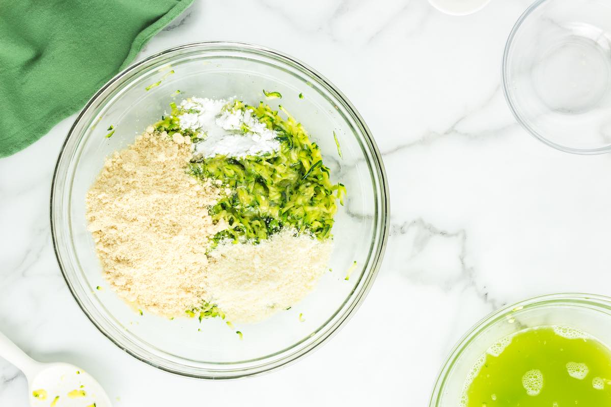 shredded zucchini, eggs, seasoning, and bread crumbs in a bowl.