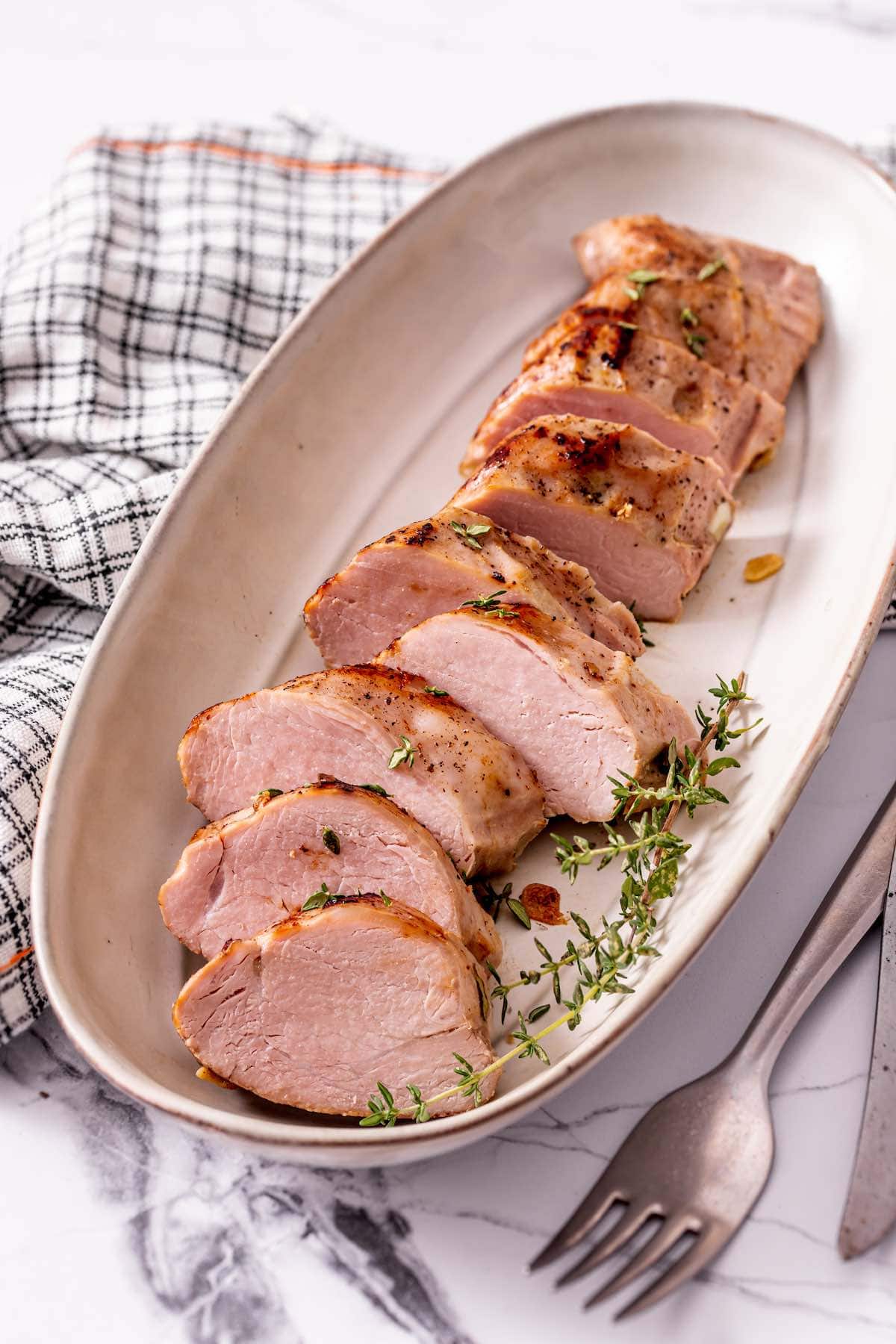 sliced sous vide pork tenderloin on a serving dish.