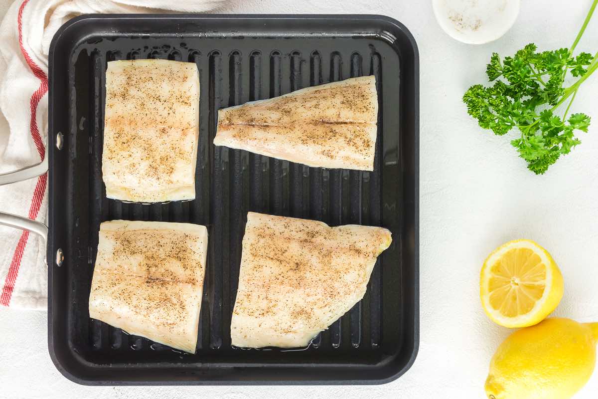 raw seasoned grouper on a grill pan.