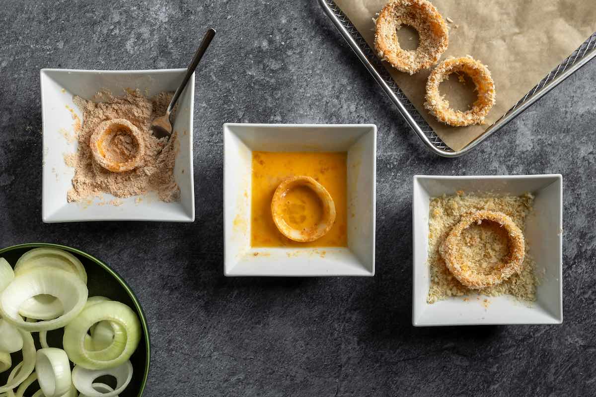 dredging raw onion rings in egg wash, flour, and bread crumbs.