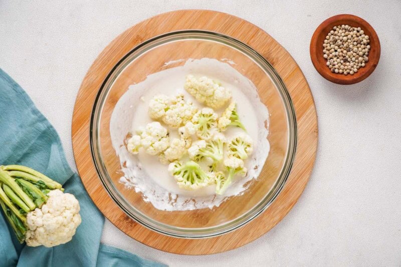 raw cauliflower in a bowl with seasonings.