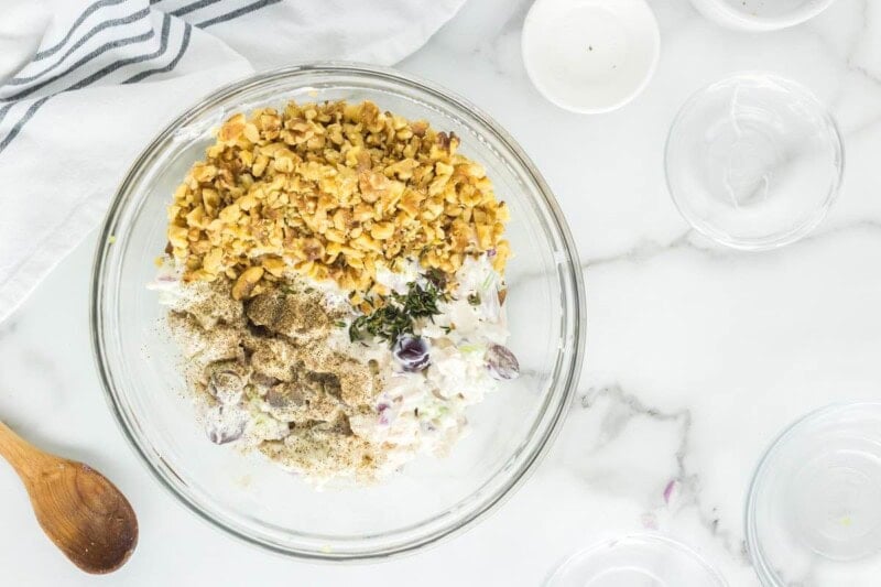 chopped chicken, nuts, mayonnaise, yogurt, and grapes in a bowl.