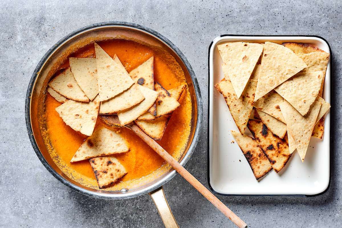 mixing tortilla chips in homemade salsa.