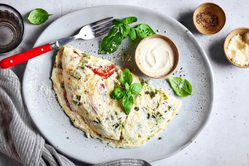 egg white omelette on a plate with fresh herbs and parmesan cheese.