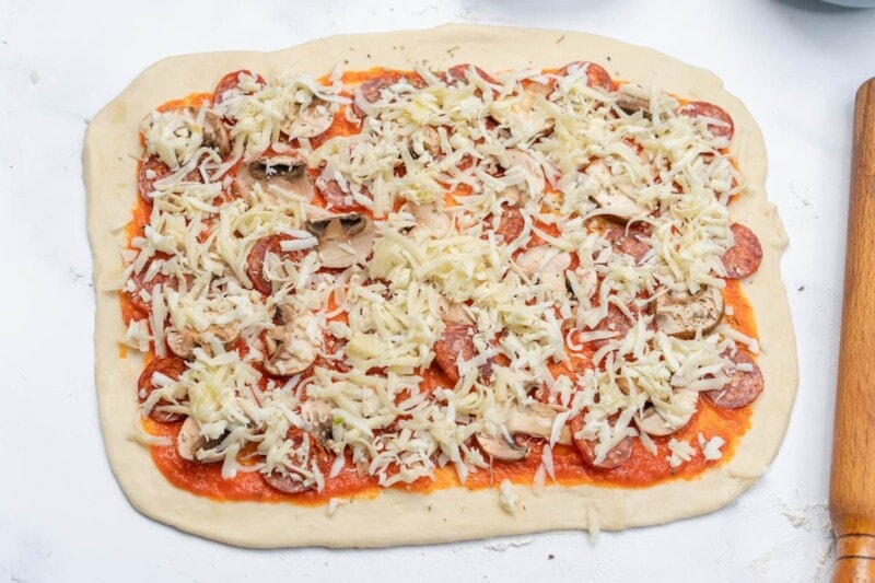 dough with tomato sauce and pizza toppings.