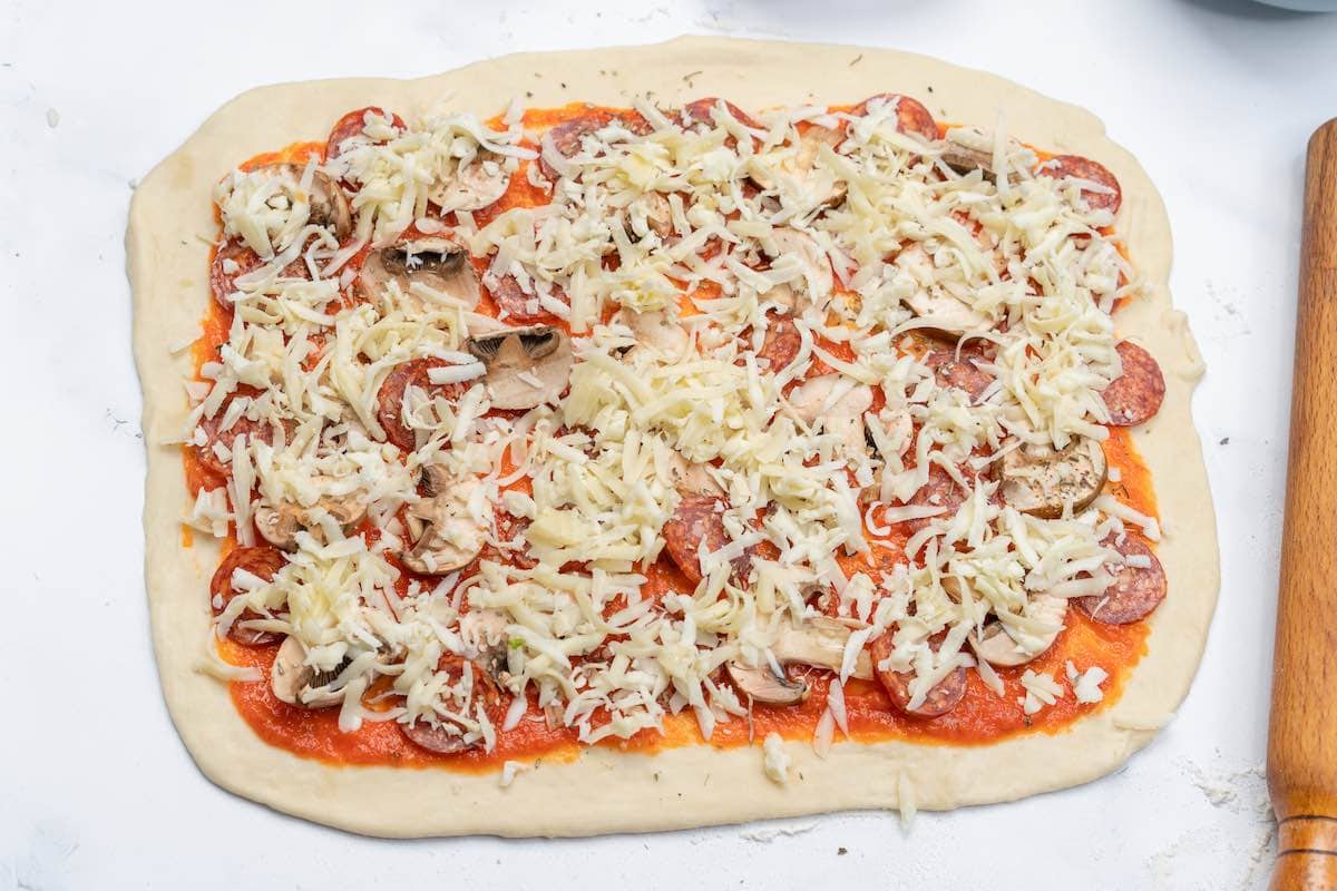 dough with tomato sauce and pizza toppings.