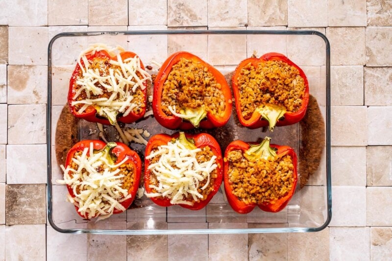 filling red bell peppers with stuffing mixture and cheese.