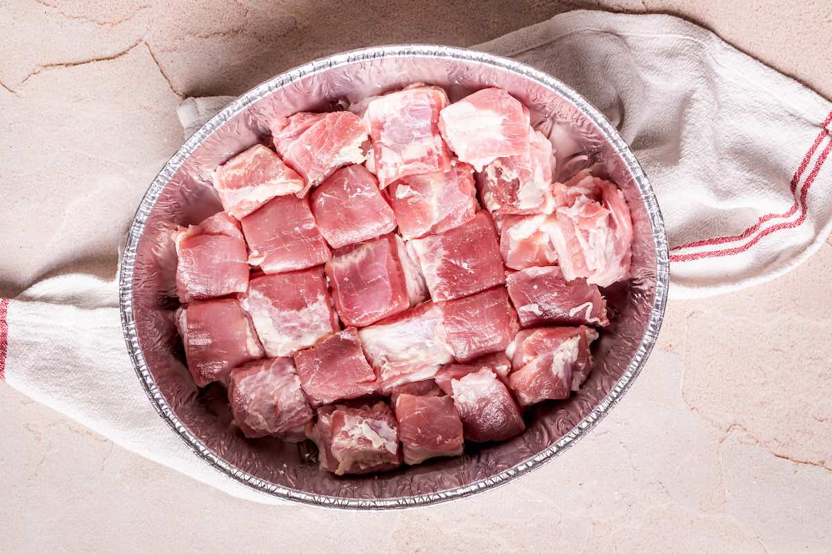 raw pork belly bites in baking dish.