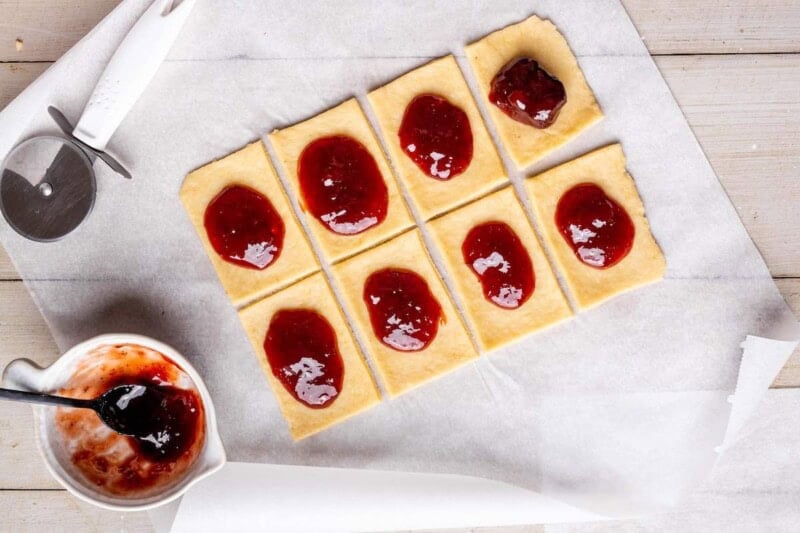 adding strawberry jam on top of dough.