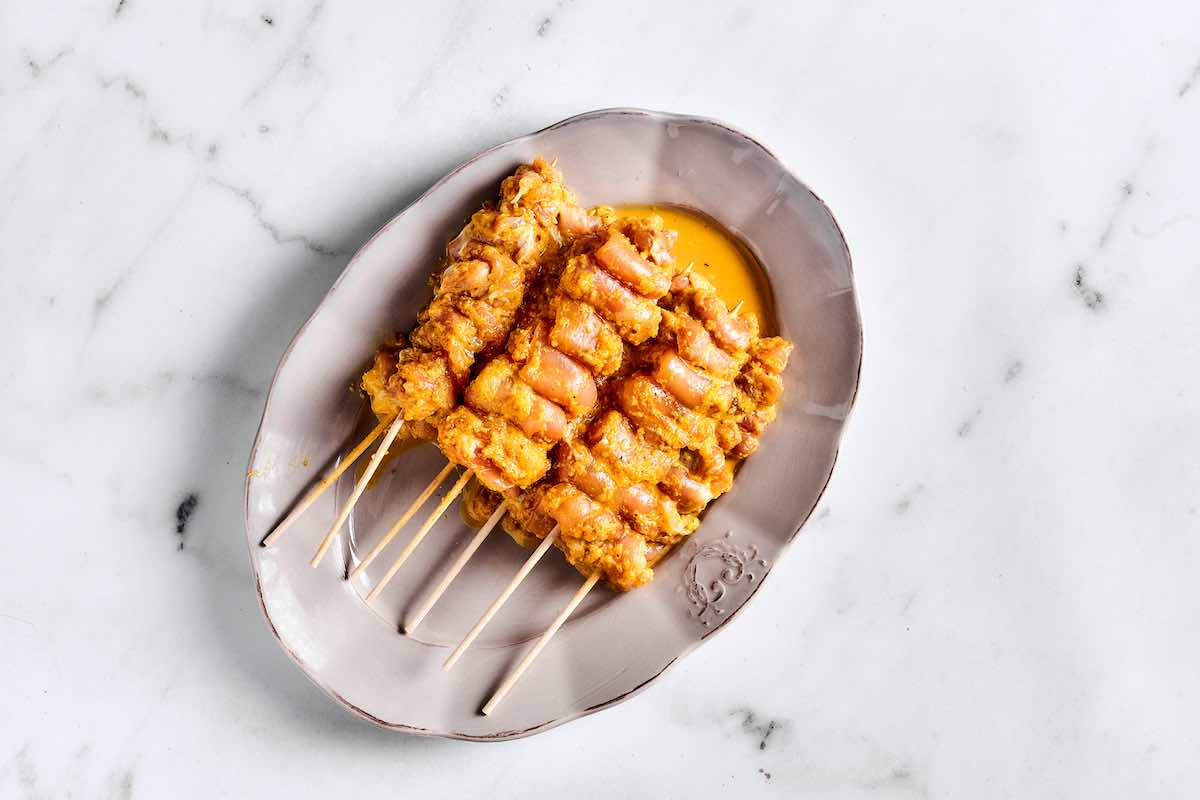 raw chicken skewered on wooden skewers.