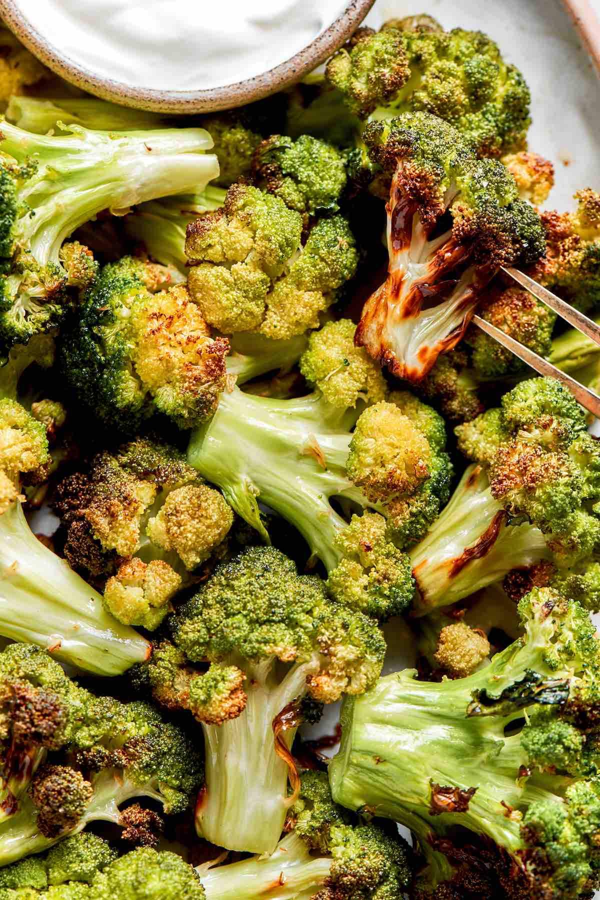 air fried broccoli on a plate with dipping sauce.