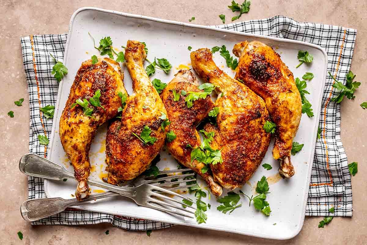 oven baked chicken leg quarters on a serving plate.