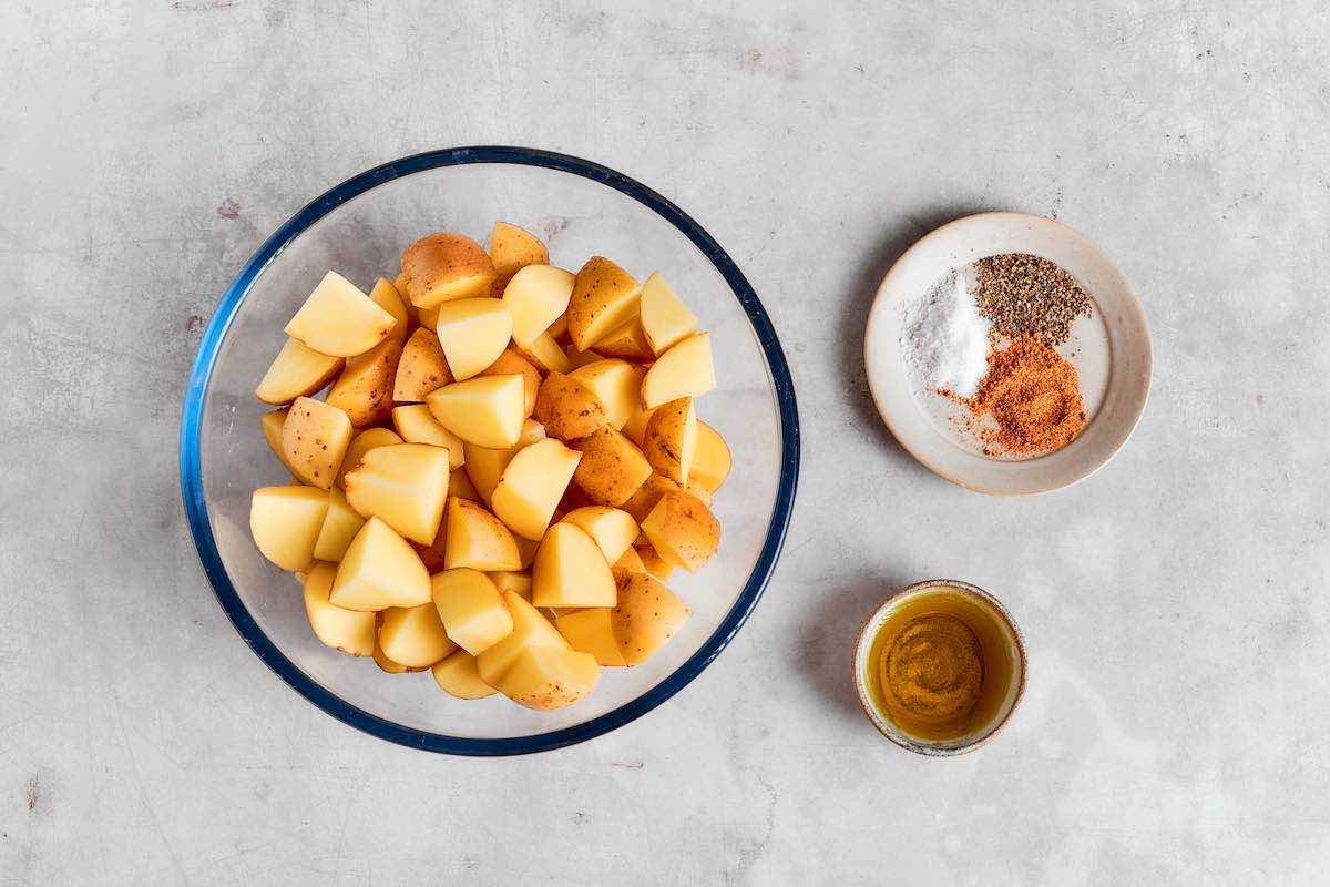 raw potatoes and seasonings in bowls. 