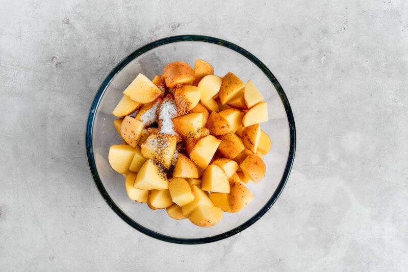 seasoned raw potatoes in a bowl.