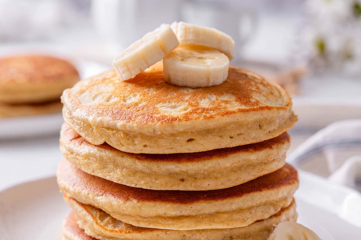 fluffy banana protein pancakes with sliced banana on top.