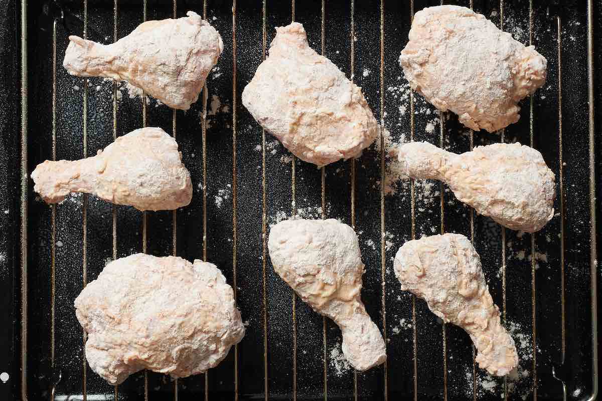 breaded raw chicken pieces on a wire rack.