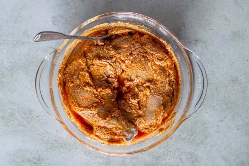 raw chicken marinating in a bowl.