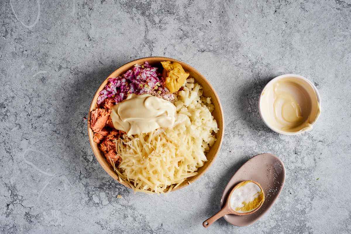 shredded cheese, tuna, chopped onions, mustard, and cauliflower in a bowl.