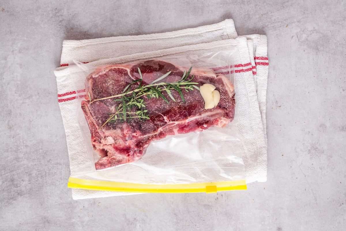 vacuum sealed steak with rosemary, thyme, and garlic.