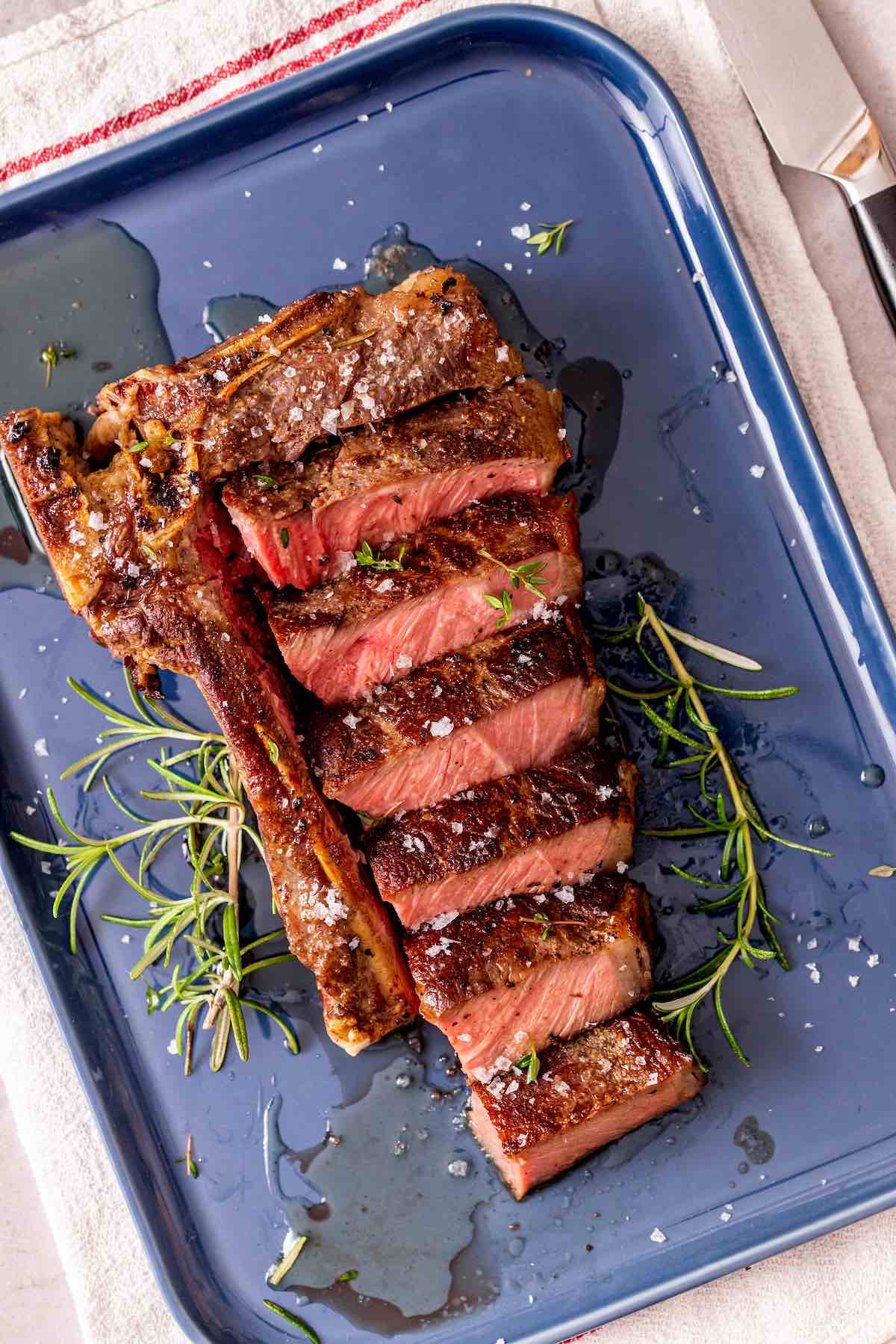 sliced sous vide steak with fresh herbs and flaky salt.